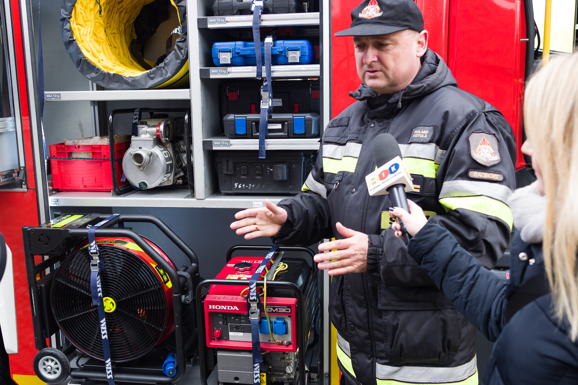 Bryg. Roland Kotula dowódca JRG w Raciborzu prezentuje wyposażenie nowych wozów strażackich, tutaj wentylator oddymiający zasilany na akumulator